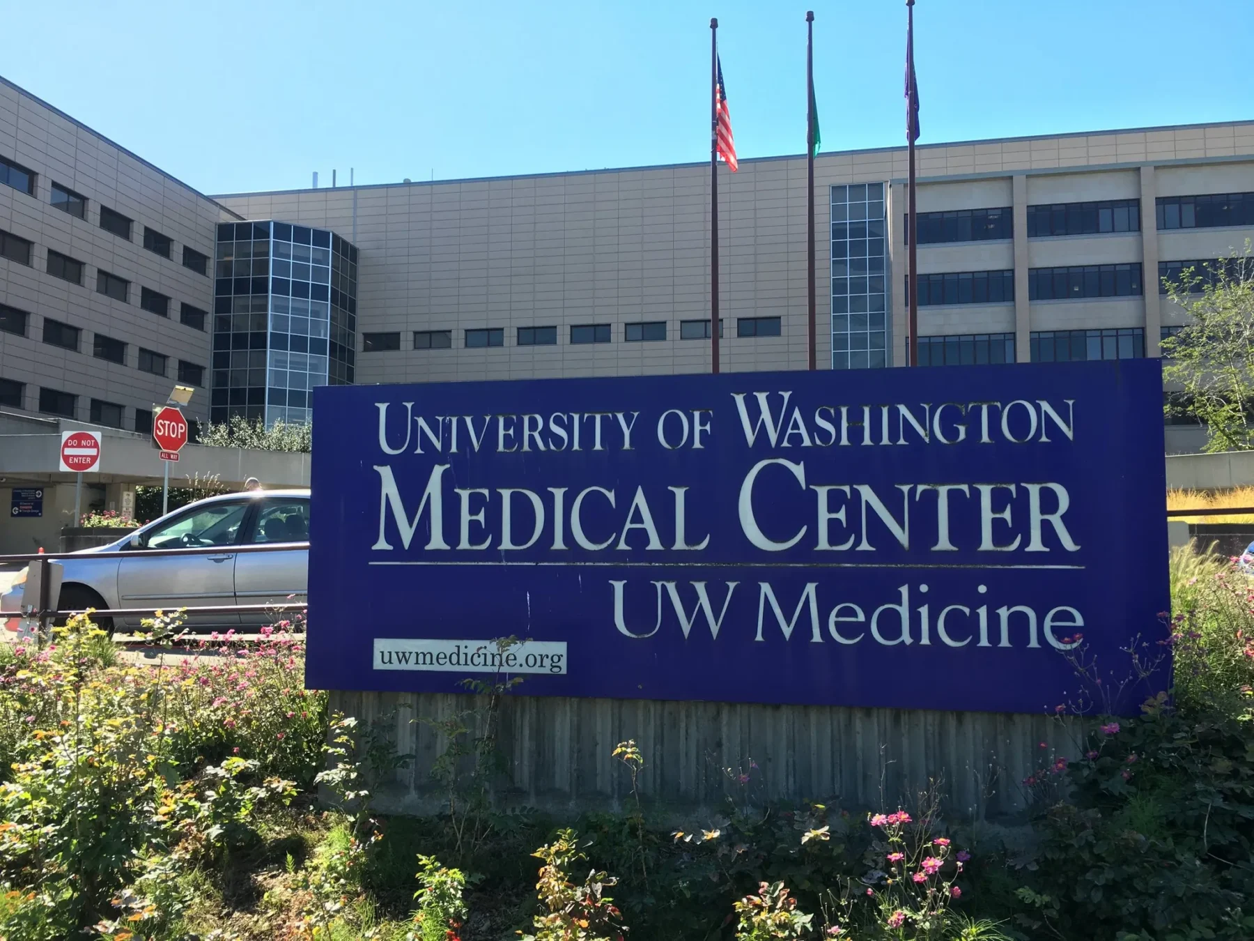 The blue and white sign that reads University of Washington Medical Center, with the hospital in the background.