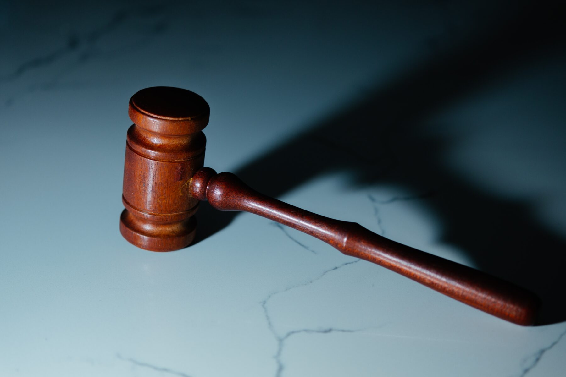 A wooden gavel sitting on a white marble surface