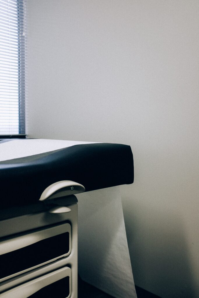 The corner of a medical exam table against a blank wall.