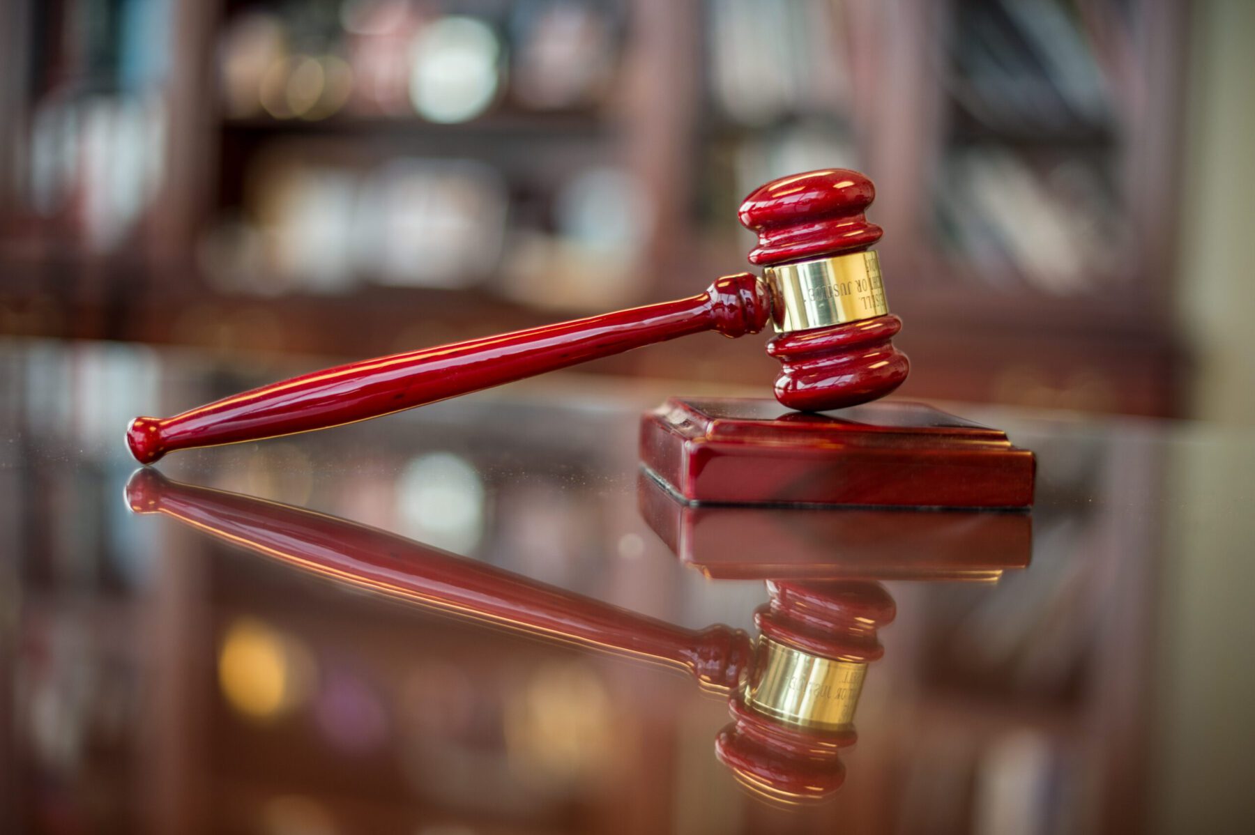 A wooden gavel on a shiny wooden table.