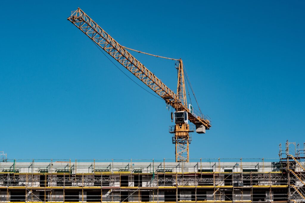 A large yellow crane on a rooftop against the blue sky.