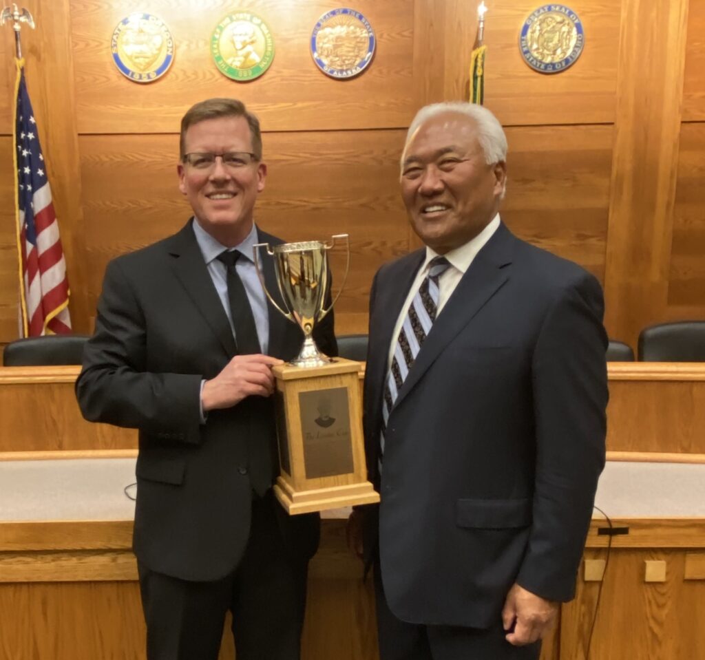 George Ahrend (left) and Mark Kamitomo (right) holding the Linden Cup trophy in the mock courtroom at Gonzaga University