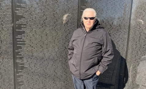 Charlie Bourg standing in front of the engraved wall at the Vietnam Veterans Memorial in Washington DC